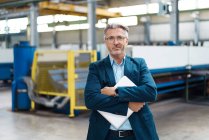 Portrait of a confident mature businessman holding laptop in a factory — Stock Photo
