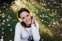 Счастливая красивая женщина слушает музыку, сидя в парке — стоковое фото