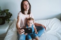 Mother and baby girl taking a selfie with smartphone at home — Stock Photo