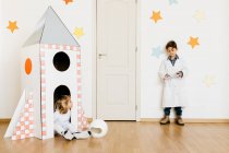 Siblings playing astronaut and researcher at rocket — Stock Photo