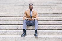 Ritratto di giovane uomo d'affari sicuro seduto sulle scale — Foto stock