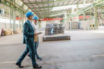 Dois empresários tendo uma reunião e andando em uma fábrica — Fotografia de Stock