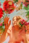 Belle femme derrière verre ane toucher des fleurs — Photo de stock