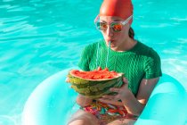Retrato de mujer con neumático flotante y sandía en piscina - foto de stock