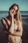 Primo piano di giovane donna con gli occhi chiusi che indossa bikini in piedi contro il mare durante il tramonto — Foto stock