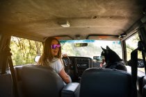 Sorridente donna guida auto mentre seduto con husky — Foto stock