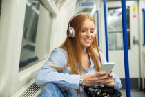 Schöne junge Frau hört Musik, während sie im Zug sitzt — Stockfoto