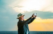 Senior fotografiert mit Smartphone bei Sonnenuntergang — Stockfoto