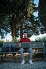 Empresario usando portátil mientras está sentado en el banco en el parque - foto de stock