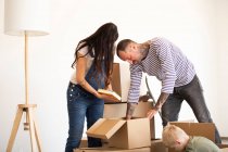Famille déballer des boîtes en carton contre le mur dans une maison neuve — Photo de stock