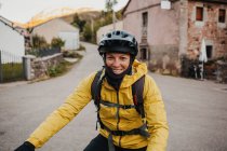 Посміхнена жінка середнього віку в теплому одязі їде на гірському велосипеді по дорозі в Сомєдо природного парку (Іспанія). — стокове фото