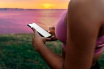 Close-up of fit woman using smart phone during sunset — Stock Photo