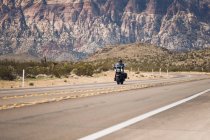 Man riding motorcycle on highway against mountain, Nevada, USA — Stock Photo