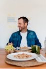 Счастливый мужчина-профессионал с едой на столе, глядя в сторону в гостиной — стоковое фото