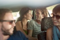 Casal sorridente com amigos sentados no carro durante a viagem de carro — Fotografia de Stock