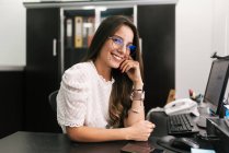 Посмішка бізнес-жінка сидить з головою в руках в офісі — стокове фото
