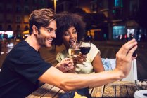 Uomo che prende selfie con la ragazza mentre brinda al vino con lei a data notte — Foto stock