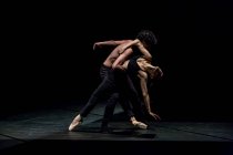 Männliche und weibliche Tänzer führen zeitgenössisches Ballett auf schwarzer Bühne auf — Stockfoto