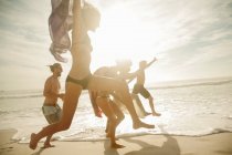 Amici allegri che saltano in spiaggia nella giornata di sole — Foto stock