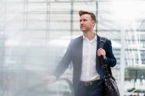 Businessman with bag walking by escalator in city — Stock Photo