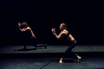 Männliche und weibliche Tänzer führen zeitgenössisches Ballett auf schwarzer Bühne auf — Stockfoto