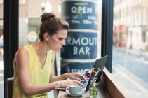 Young businesswoman using laptop at coffee shop — Stock Photo