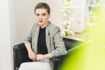 Confident female entrepreneur wearing blazer sitting on armchair at home — Stock Photo