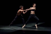Männliche und weibliche Tänzer führen zeitgenössisches Ballett auf schwarzer Bühne auf — Stockfoto