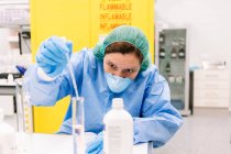 Farmacista femminile miscelazione sostanze chimiche in cilindro graduato in laboratorio — Foto stock