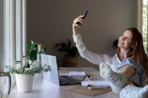 Femme souriante utilisant un téléphone portable tout en étant assis à la maison — Photo de stock