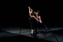 Männliche und weibliche Tänzer führen zeitgenössisches Ballett auf schwarzer Bühne auf — Stockfoto