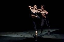 Männliche und weibliche Tänzer führen zeitgenössisches Ballett auf schwarzer Bühne auf — Stockfoto