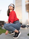 Jeune femme portant des lunettes de soleil accroupi sur le sentier de la ville — Photo de stock
