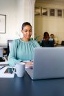 Smiling businesswoman working on laptop at office desk — Stock Photo