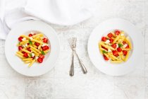 Due piatti di pasta vegetariana con mozzarella, pomodorini e basilico — Foto stock