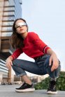 Femme élégante avec des lunettes de soleil accroupi sur le sentier en ville — Photo de stock
