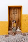 Зрелая женщина слушает музыку через наушники, сидя напротив старой двери — стоковое фото