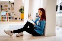 Donna d'affari che utilizza il computer portatile mentre seduto sul pavimento in ufficio — Foto stock