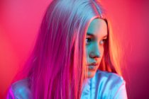 Close-up of thoughtful young woman wearing wig against pink background — Stock Photo