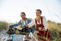 Молодий чоловік і жінка ходять велосипедами проти ясного неба. — стокове фото