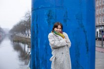 Femme en vêtements chauds debout contre la structure bleue — Photo de stock