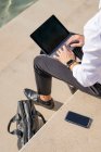 Businessman using digital tablet while sitting on steps during sunny day - foto de stock