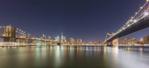 USA, New York, New York City, Brooklyn Bridge and Manhattan Bridge illuminated at night - foto de stock