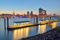 Germany, Hamburg, Northern bank of Elbe at dawn with Elbphilharmonie and city skyline in background — Stock Photo