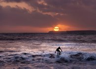 Silhouette man surfing on sea against cloudy sky at sunset, Pembrokeshire, Galles, Regno Unito — Foto stock