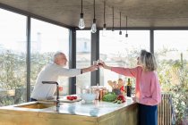 Senior coppia brindisi bevanda mentre in piedi in cucina a casa — Foto stock