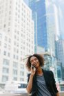 Empresária falando no celular enquanto está em frente a prédios de escritórios na cidade — Fotografia de Stock