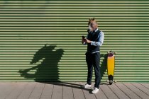 Мужчина предприниматель в маске лошади с помощью мобильного телефона, стоя у стены — стоковое фото