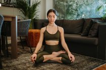 Woman meditating in living room at home — Stock Photo