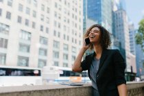 Rindo afro profissional feminino falando no telefone inteligente enquanto está na cidade — Fotografia de Stock